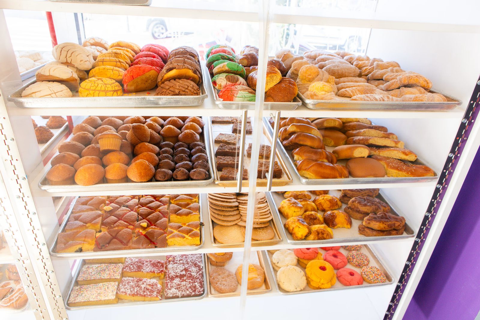 Mostrador de pan dulce lleno de conchas, bollos, galletas y otros panes.